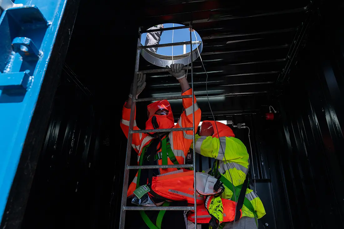 Two delegates wearing full body PPE and hi-vis in a confined space tank undertaking a HSS Training course