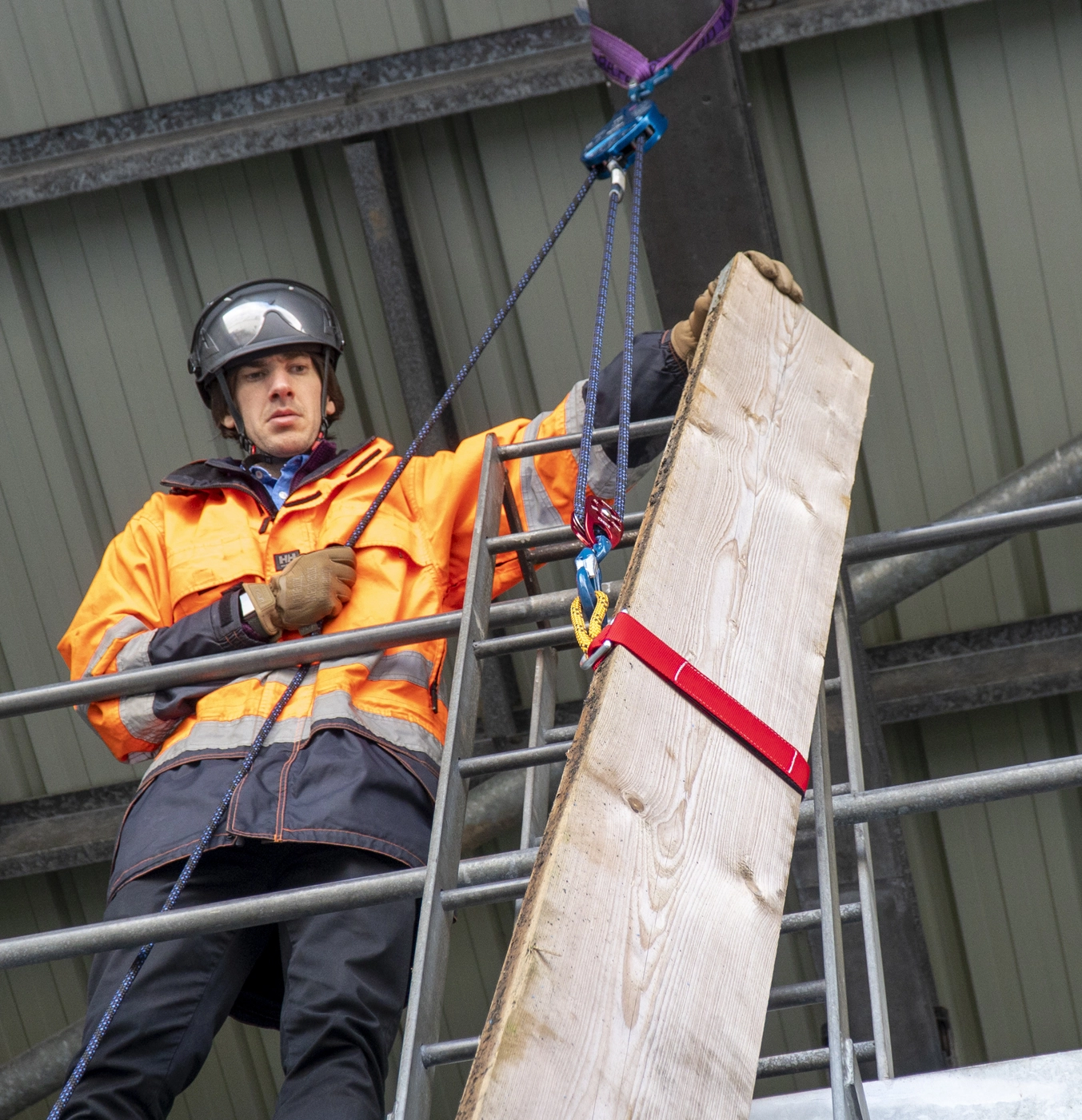 Closeup shot of a piece of timber being lifted onto scaffolding via a hoist